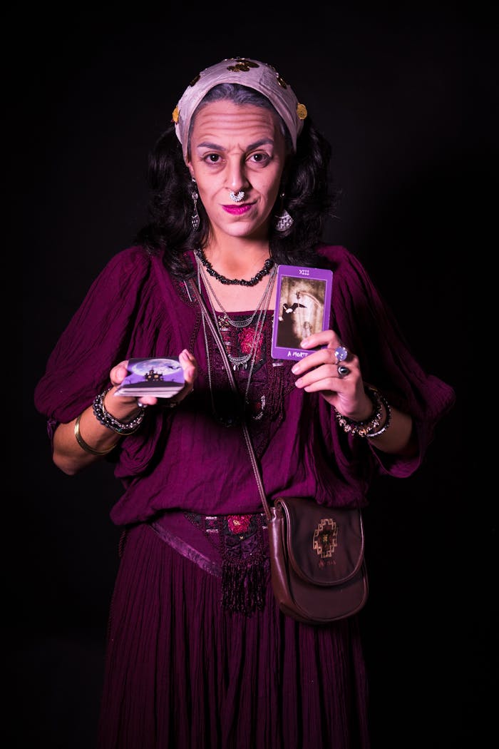 A colorful fortune teller poses with tarot cards in a studio setting in São Paulo.