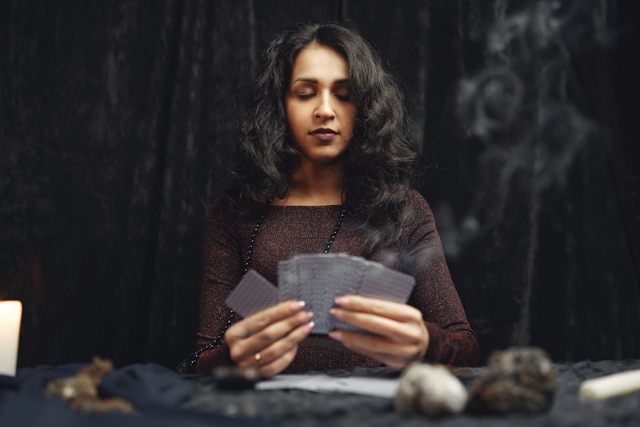 A woman engaging in a spiritual card reading session with candles, smoke, and crystals.