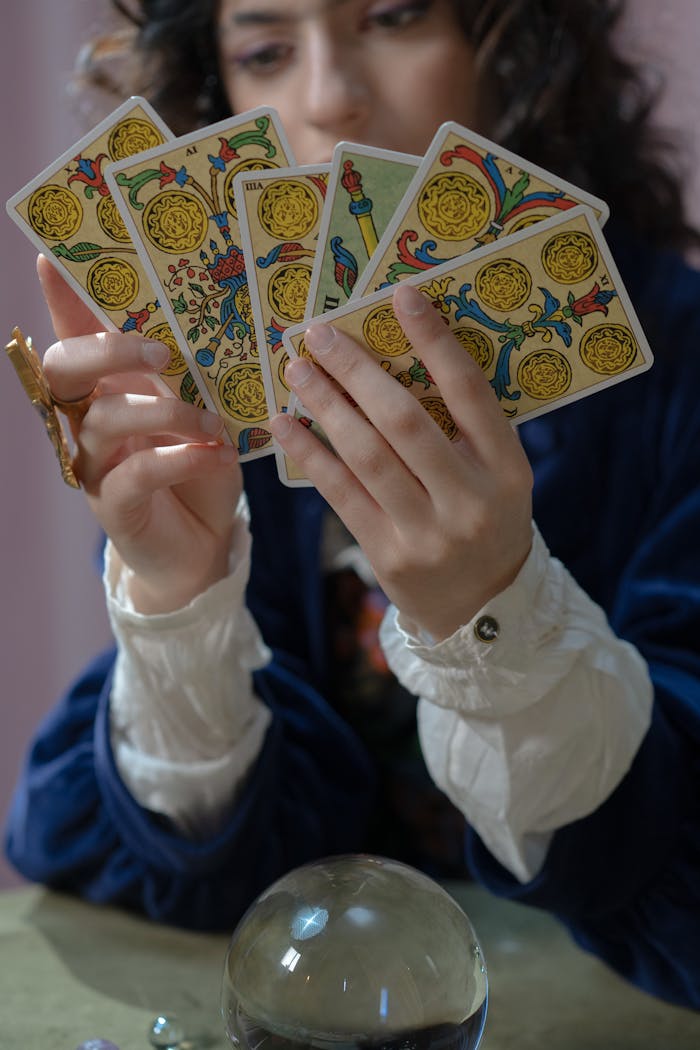 A woman in dim light holding tarot cards, suggesting fortune-telling or spiritual guidance.