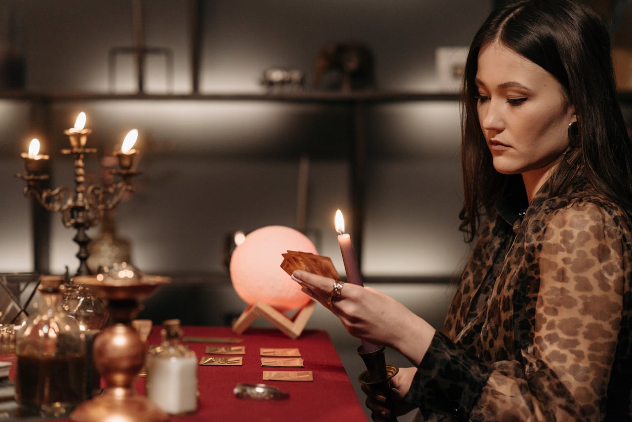 A woman engages in a mystical tarot reading by candlelight, creating an enchanting atmosphere.